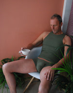 Load image into Gallery viewer, Man relaxing in chair holding a coffee cup wearing Hollywood khaki Boxers and Racer Back Vest by Moot Lingerie for men
